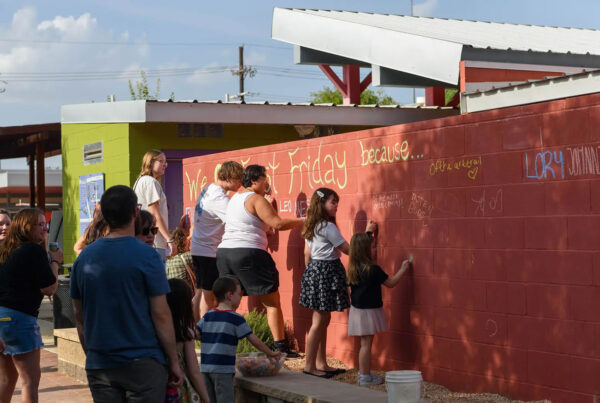 First Friday Art Trail attendees write what they love about the monthly event on a wall outside of the Louise Hopkins Underwood Center for the Arts gallery during First Friday Art Trail in Lubbock on Aug. 2.