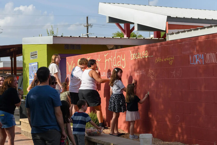 First Friday Art Trail attendees write what they love about the monthly event on a wall outside of the Louise Hopkins Underwood Center for the Arts gallery during First Friday Art Trail in Lubbock on Aug. 2.